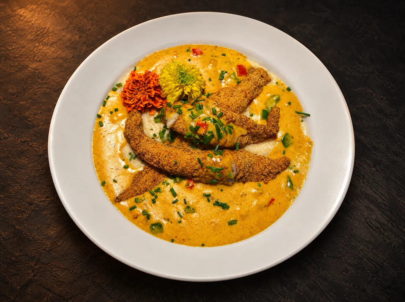 Cornmeal-crusted fried catfish over grits with Creole cream sauce and chives