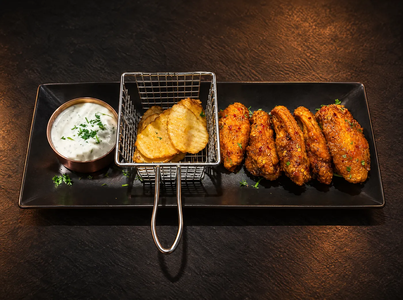 Margarita wings with wavy fries and ranch dip on a black plate